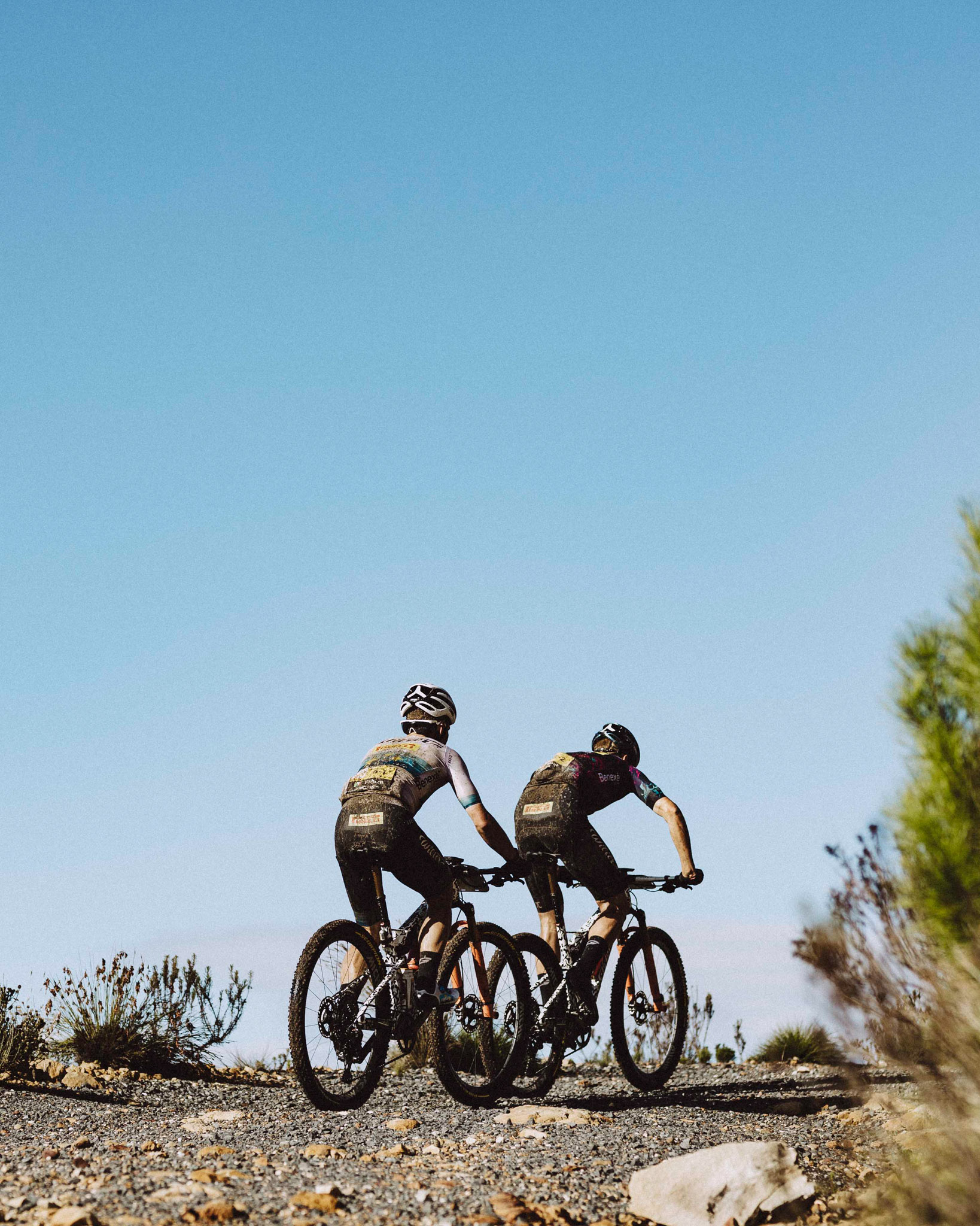 Two cyclists riding along a gravel road